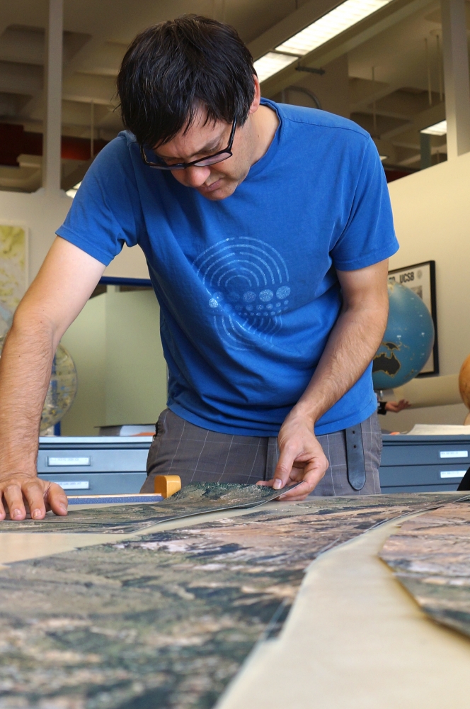 man in blue shirt cutting out map photos
