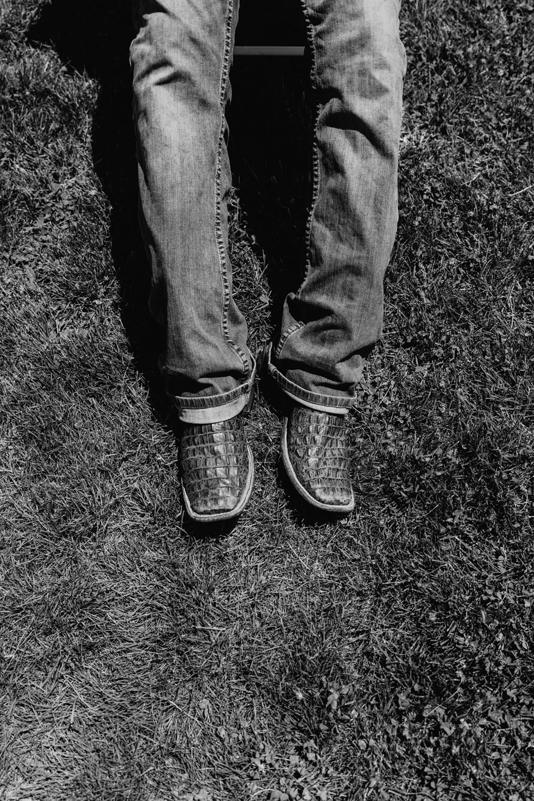 black and white photo of the legs of a student in alligator boots