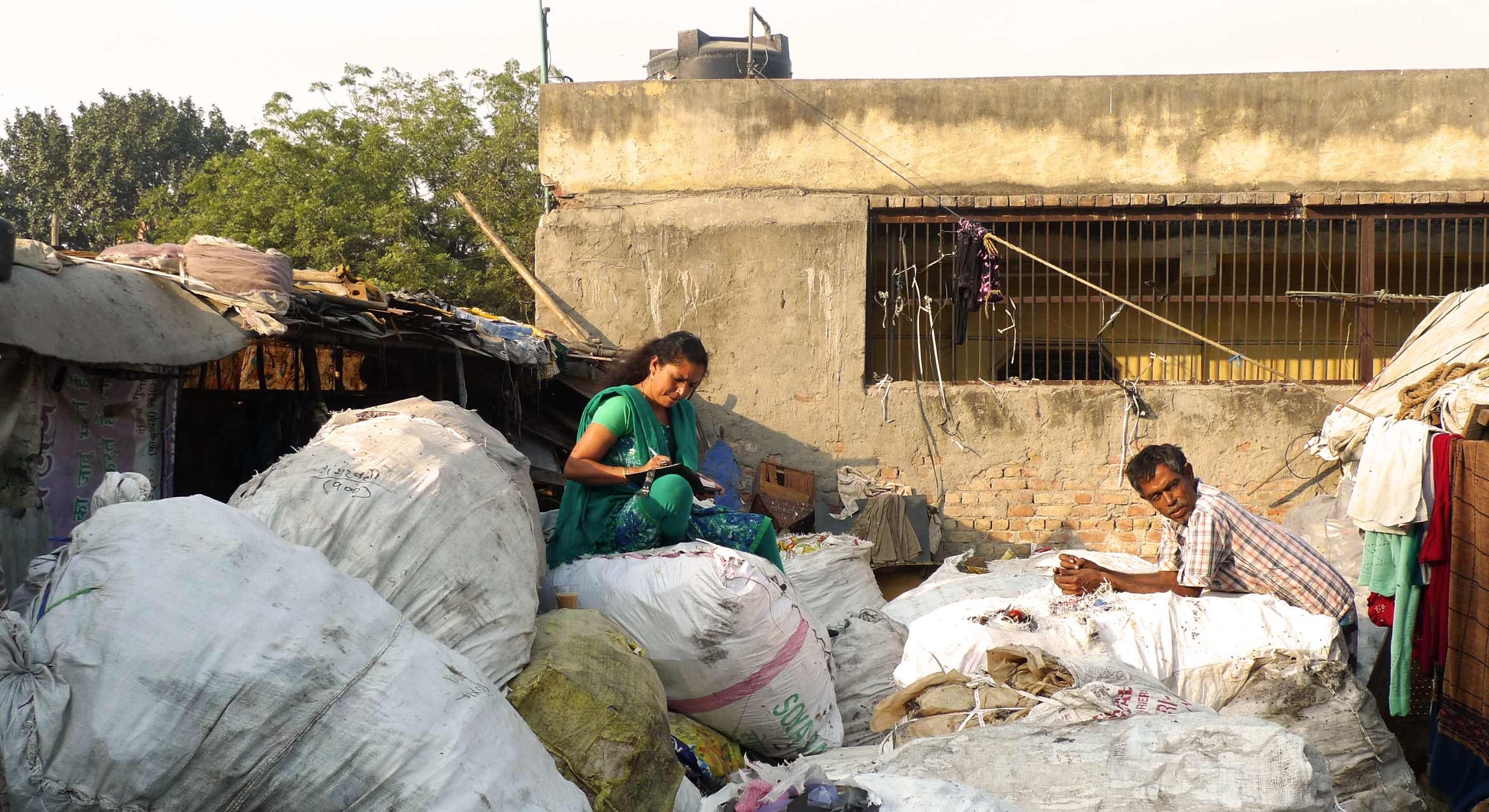 people in India working on top of large bags of waste