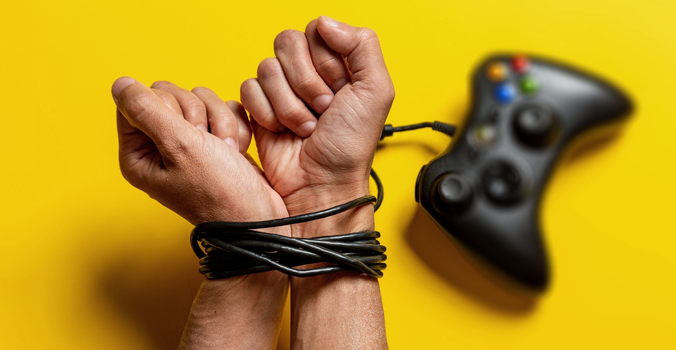 photograph of hands bound by the cord of a video game controller