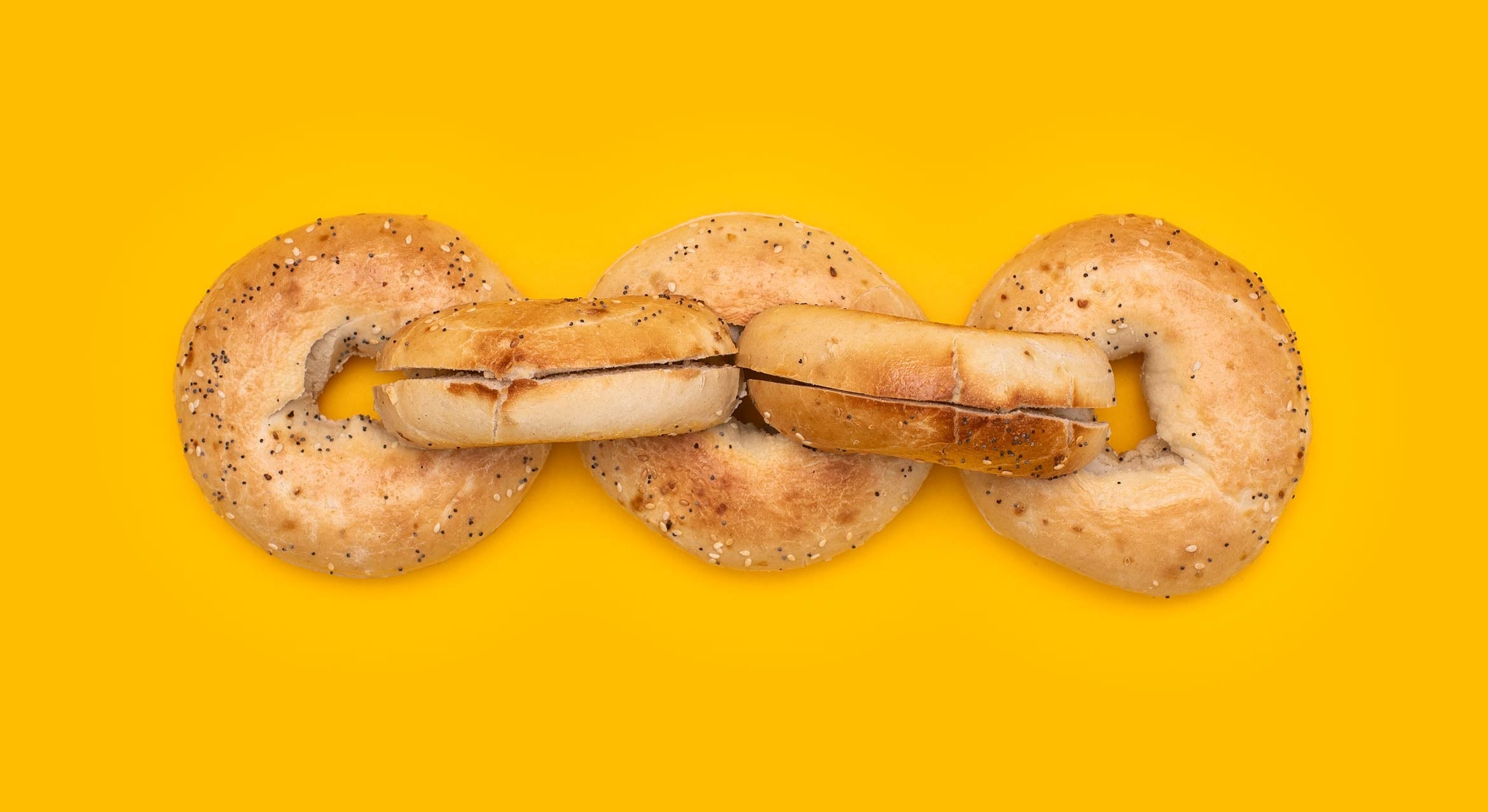 Five sliced bagels are linked in a chain on a yellow background.