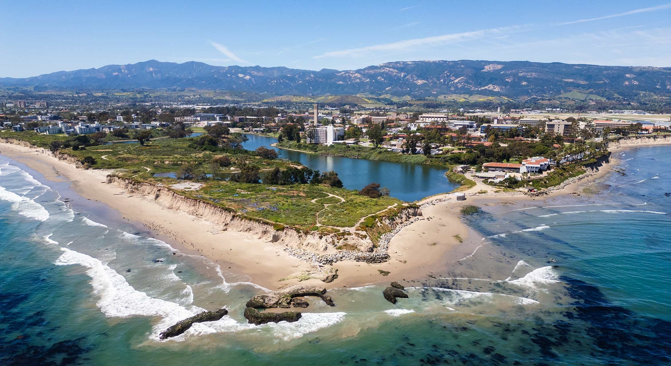 Aerial view of the ocean, beach and mountains surrounding a university campus